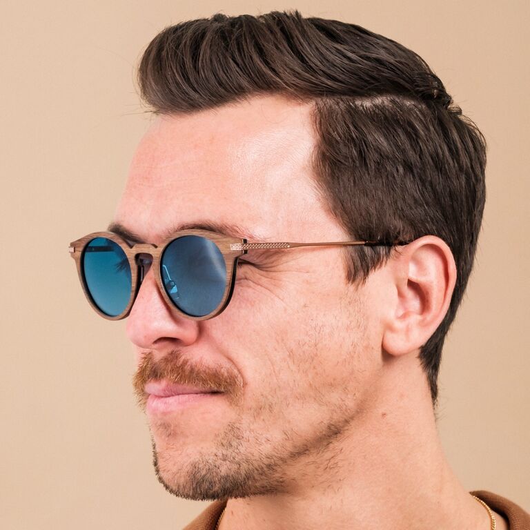 "The Maverick" zonnebril met een walnotenhouten montuur en bronzen accenten met blauwe glazen.