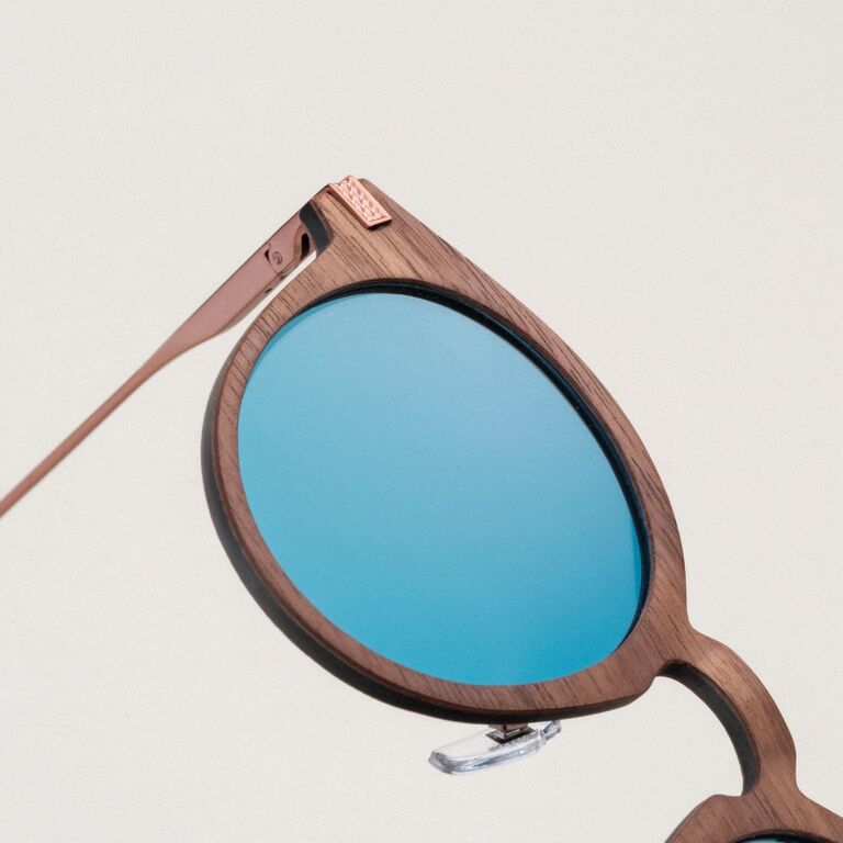 "The Maverick" zonnebril met een walnotenhouten montuur en bronzen accenten, met een strak, modern design.